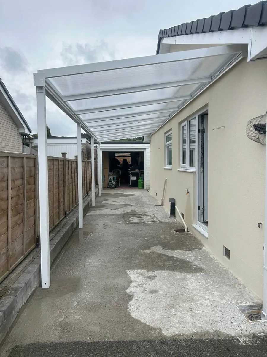 White-framed canopy alongside a home providing covered access to a garage